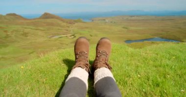 Ayaklar, yürüyüş ve dağdaki ayakkabılar barış, keşif ve açık hava egzersizi için. Sağlık, seyahat ve macera için İskoçya 'da tatil ve manzara için sırt çantası, pov ve yeşil arazi.