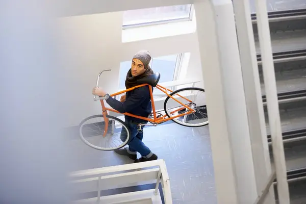 Bicycle, stairs and man in a building carrying bike for healthy and eco friendly transportation for travel. Staircase, carry and cyclist with apartment complex, take up and journey of walking steps.