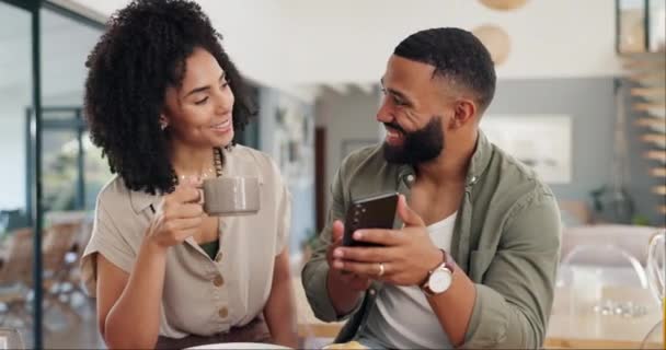 ソーシャルメディアのためのスマートフォンとカップル 幸せでコーヒー 音楽やアプリの説明を共有します 朝食付きのキッチンでの男性 リラックスしてオンラインウェブサイトでスクロール — ストック動画
