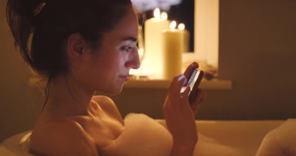 Noc Kąpiel Bąbelkami Kobieta Telefonem Komórkowym Pisanie Higiena Świecami Rutyną — Wideo stockowe