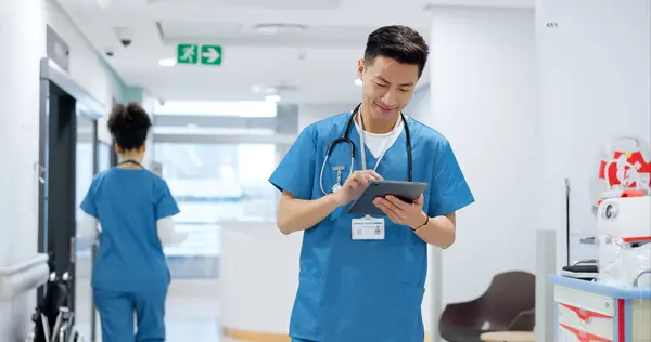 Walking, tablet or doctor in hospital with research on social media to search for medicine info online. Asian man reading, smile or medical healthcare nurse browsing on technology for telehealth news.