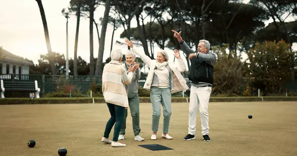 Bowls, celebration and hugging with senior friends outdoor, cheering together during a game. Motivation, support or applause and a group of elderly people clapping while having fun with a hobby.