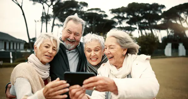 Senior people, happy or friends take a selfie in park together for a memory with smile or joy outdoors. Group, old man or elderly women taking photo or picture in nature for social media for vlogging.