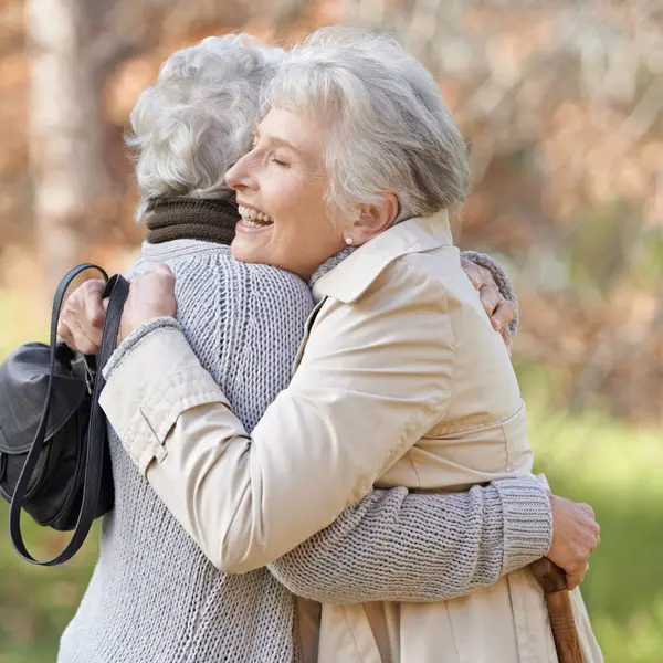 Nature, happy and elderly friends hugging for support, bonding or care in outdoor park or garden. Love, smile and senior women in retirement embracing for greeting, connection or trust in field