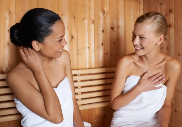 Women, relax and talking in sauna at spa with healthy detox of sweat for beauty, wellness and skincare. Friends, treatment and sitting in steam room with a smile for anti aging benefits to body.