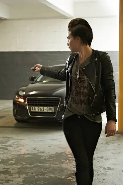 Woman, parking and lock car with cool punk style in garage for safety at home. Underground, vehicle and female person with button for security with edgy fashion and driving trasnportation and trip.