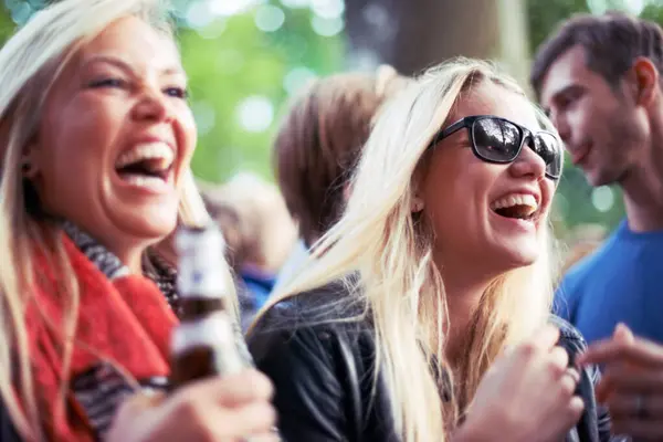 Happy, drinks and women at music festival, concert or party laughing, excited and enjoy outdoor rave or techno celebration. Young friends, audience or crowd with beer bottle or alcohol for holiday.