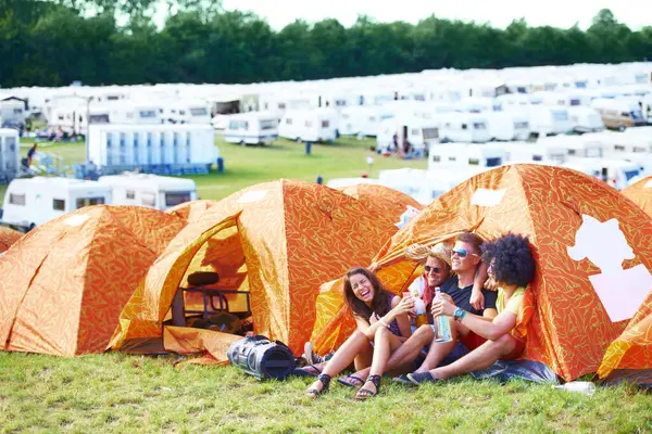 Happy friends, tent or laughing at funny festival for joke, comedy or humor at outdoor campsite. Friendship, young group or people enjoying fun holiday weekend, event or camping out on grass at party.