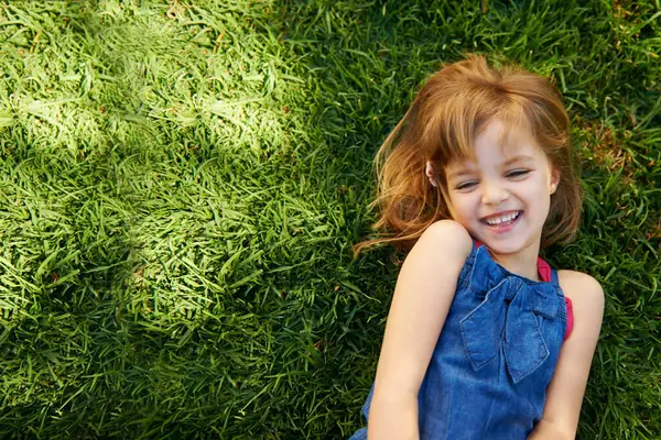 Child, grass and smile from above for relax holiday in countryside for summer vacation, nature or park. School kids, and happy on garden lawn in California environment for outdoor, sunshine or mockup.