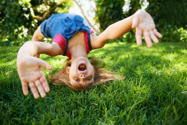 Child, back and bend or bridge for play in summer or flexibility game or practice, fun or backyard. Kid, face and hands or gymnastics stretching with head balance on grass in London, happy or garden.