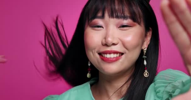 アジアの化粧品 メイク ピンクのバックグラウンドで美のためのスタジオでブローキスで女性 ビデオコール コミュニケーション愛 ジェスチャー 自信のための女性 モックアップスペース — ストック動画