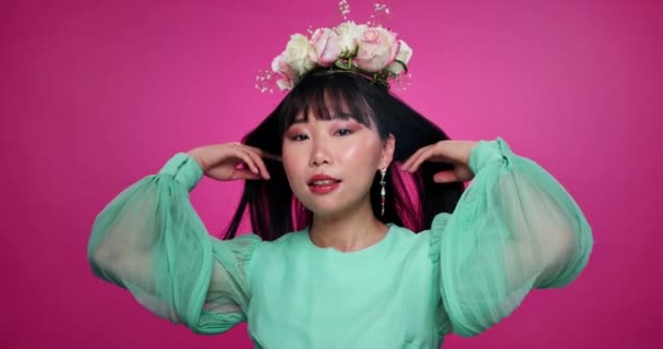 ピンクのバックグラウンドで隔離されたスタジオで髪に花冠を持つ顔 美しさ アジアの女性 有機スキンメイク ファッション 笑顔の自然韓国モデルのポートレート リース 花の化粧品 — ストック動画