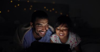 Gece, yatak ve kız ile baba, tablet ve internet ile gülümseme ve kitap ile bağlanma. Ailesi, babası ve kızı teknoloji ve karanlığa sahip. Mutluluk ve sevgiyle dijital uygulama, ev ya da neşeli..