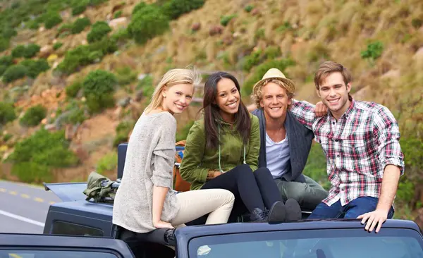Happy friends, portrait and road trip in roof of car for holiday weekend, travel or outdoor vacation. Excited group of young people hug, smile or relax on convertible vehicle for adventure or journey.