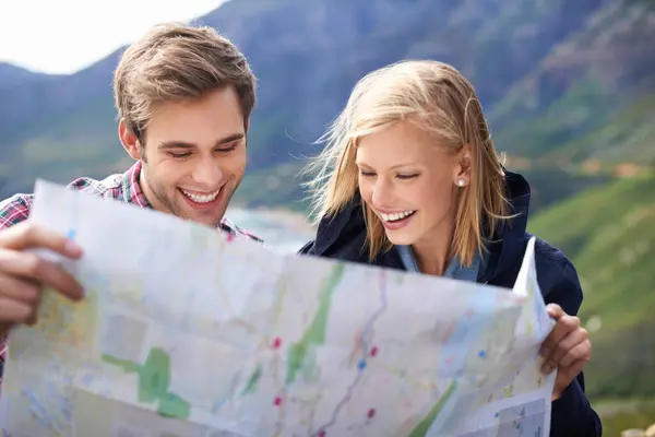 Happy people, friends and map with location for travel or destination on mountain in nature. Young couple with smile, document or geographic paper with routes for navigation, help or outdoor tourism.
