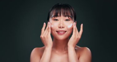 Cilt bakımı, krem ve yüz. Stüdyodaki Asyalı kadın. Kolajen ürünü, nemlendirici ve güzellik rutini. Dermatoloji, kozmetik ürünleri ve esmer arka planda yaşlanmayı önleyen losyonlu bir kız.