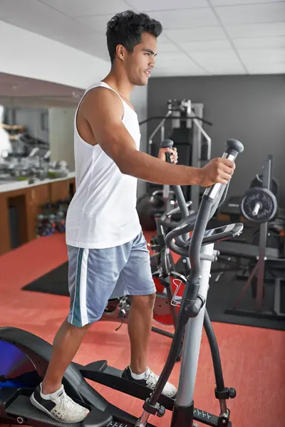 Fitness, health and man with air walker in gym for commitment to cardio improvement workout routine. Exercise, running or walking with confident young athlete on equipment for full body training.