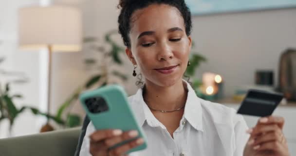自宅のオンラインショッピング Eコマースのための女性 クレジットカード ソファーでフィンテックの支払い バランス インターネットバンキング プレミアムサブスクリプションをチェックするモバイルを持つ幸せなアフリカ人 — ストック動画