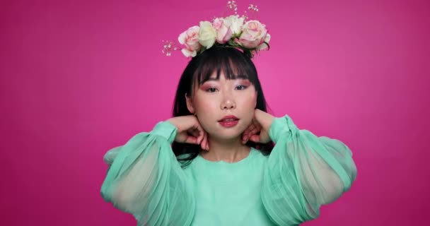 ピンクの背景に美しさ 化粧品を備えたアジア女性の花冠 ファッション フェイス 花の美しさとスタジオでメイク 有機製品を持つ人の肖像 — ストック動画