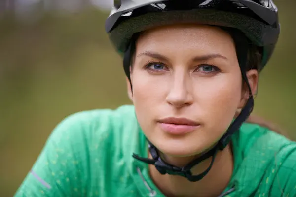 Portrait, cycling and helmet with woman closeup in nature for fitness, training or off road hobby. Face, exercise and health with confident young athlete or cyclist outdoor in countryside for cardio.