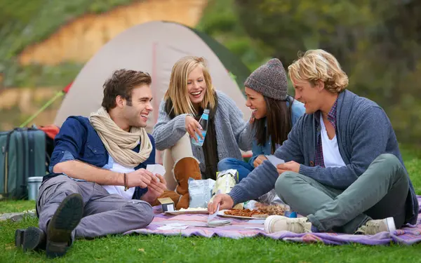 Nature, camping and people on picnic with food laughing, talking and bonding on vacation. Happy, travel and group of friends eating lunch in outdoor field, park or forest on holiday or weekend trip