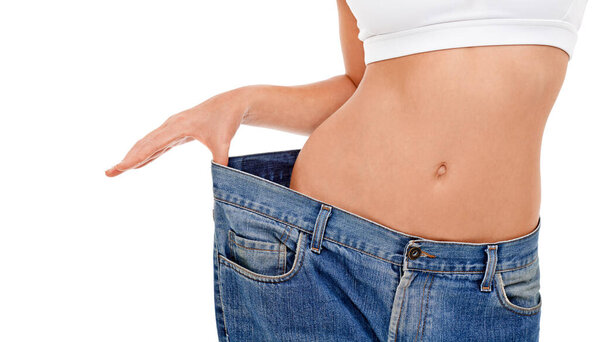 Body, health and woman with big pants in studio for weight loss, fitness or exercise results. Wellness, diet and closeup of female person with jeans for measuring slim stomach by white background