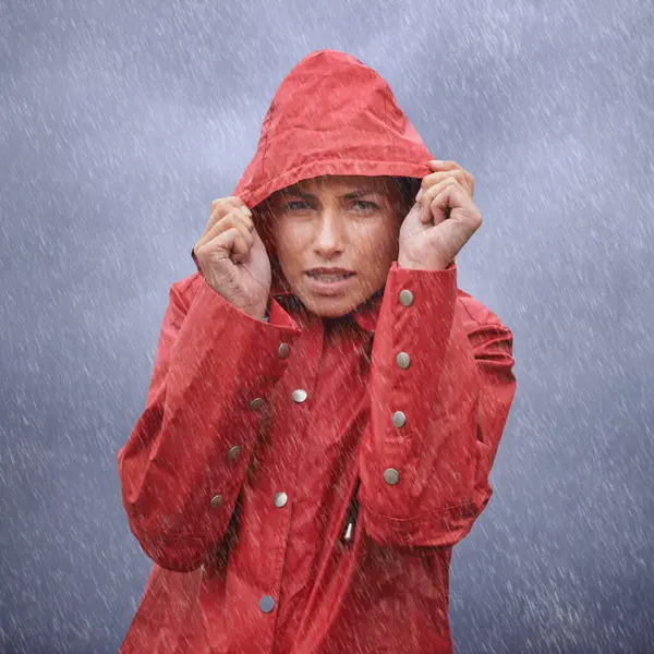 Woman, hood and portrait with rain, coat and clouds with protection in nature. Person, face and storm with cloudy, winter and waterproof hat for safety and confidence with adventure or vacation.