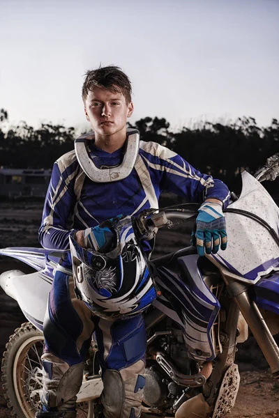 Sport, portrait and man with off road motorcycle, confidence and gear for competition, race or challenge. Adventure, adrenaline and serious face of athlete on extreme course with dirt bike in evening.