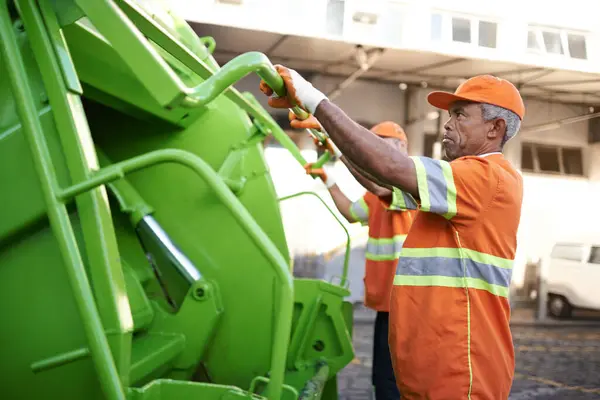 Trash, waste management and garbage truck with men in uniform cleaning outdoor on city street. Job, service and male people working with rubbish for sanitation, maintenance or collection of dirt