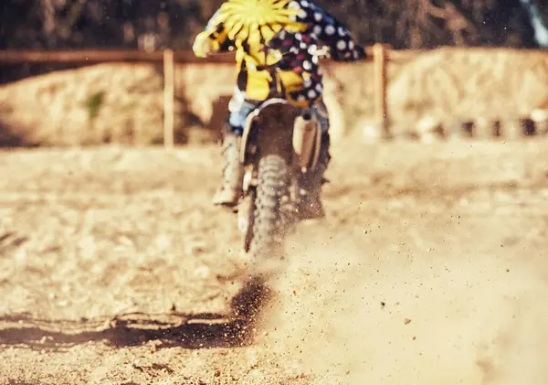 Person, motorcyclist and dust with dirt bike on track for race, extreme sports or outdoor competition. Rear view of expert rider on motorbike, scrambler or sand course for off road rally challenge.