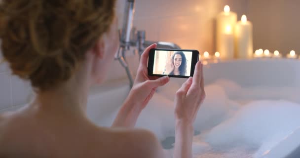 Kvinna Koppla Och Videosamtal Med Smartphone Badkaret Med Bubblor Ljus — Stockvideo
