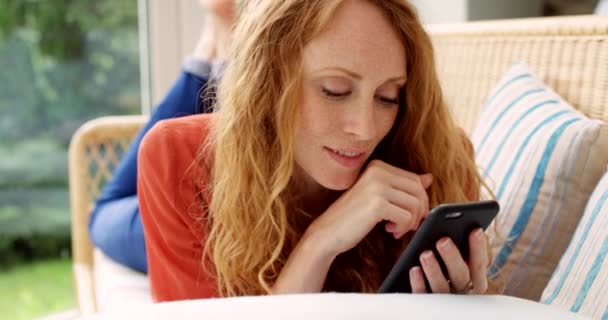 ソファーのソーシャルメディア 女性は 家庭でのインターネット接続でブログをリラックス スクロール 読書します ウェブサイト オンラインメモリ リビングルームに横たわるソファーのモバイルアプリ ポスト ガール — ストック動画