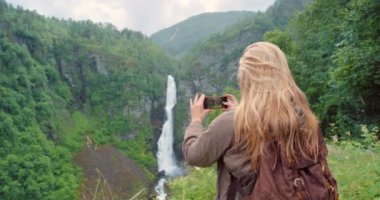 Fotoğraf, turist ya da kadın seyahat, macera ya da manzara için doğada fotoğraf çekiyor. Şelale, bayan ya da fotoğrafçı Norveç 'teki açık alan hafızası ya da konumu için fotoğraf çekiyor..