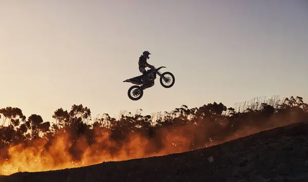 Person, jump and professional motorcyclist in the air on mockup for trick, stunt or ramp on outdoor dirt track. Expert rider on motorbike with lift off for extreme sports or rally challenge in nature.