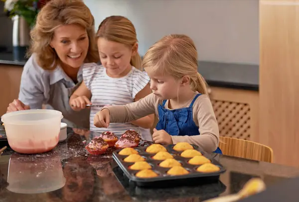 おばあちゃん 子供たち そして教えること ベーキングすること そして家で引退することの笑顔 キッチンでクリエイティブ 楽しさのためのカップケーキ 笑いとアイシングで幸せな シニア市民と少女 — ストック写真