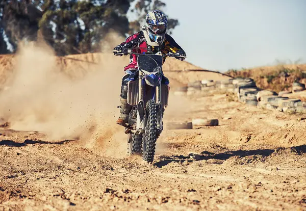 Person, motorcyclist and dust with motorbike on dirt track for race, extreme sports or outdoor competition. Professional or expert rider on bike, scrambler or sand course for off road rally challenge.