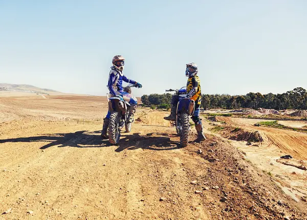 Sport, racer or relax on motorcycle outdoor on dirt road with blue sky for driving, challenge or competition. Gear, motorbike or dirtbike driver with helmet on offroad course or path for racing.
