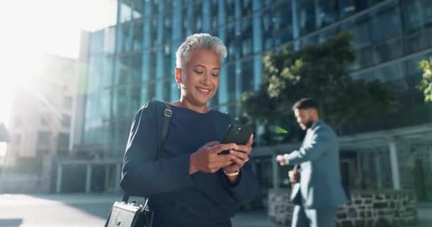 シニアの女性は 笑顔と会話で屋外でスマートフォンにテキストを送ることに満足しています レンズフレア 女性が通り ビジネスで面白いチャットで休憩中 — ストック動画