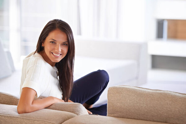 Portrait, happy and relax with woman on sofa in living room of home for free time, leisure or weekend. Smile, break and resting with young person chilling alone on comfortable couch in apartment.