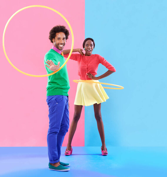 Couple, fashion and trendy in studio with colour clothes, smile and playful expression on black people together. Artistic, aesthetic in retro style for unique designer, summer fun and hula hoop.