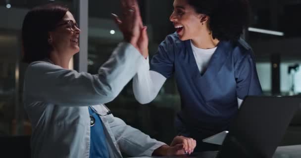 医生们 女性和快乐与高五在夜间被电脑 兴奋和成功的结果在诊所 用笔记本电脑庆祝 用反馈 分析或健康来评估目标和回顾 — 图库视频影像