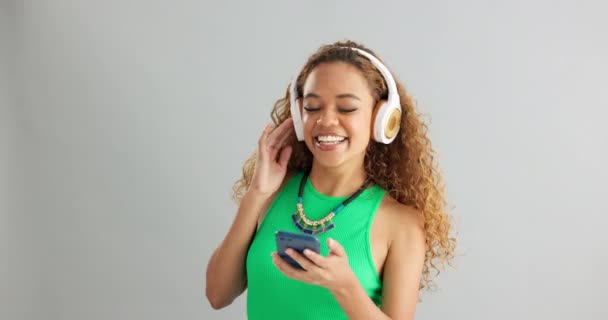 Boldog Telefon Tánc Fejhallgatóval Zenére Vagy Podcastre Szürke Stúdió Háttérrel — Stock videók