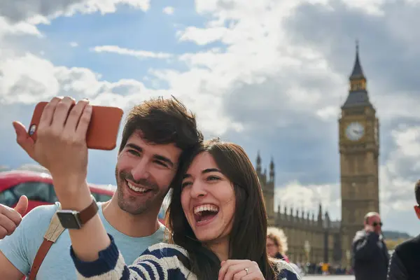 电话和夫妻在伦敦自拍 在社交媒体上张贴户外城市街道内容 大本钟 自由快乐的女人喜欢和伴侣一起在一个有趣的假日探险中拍照 免版税图库图片