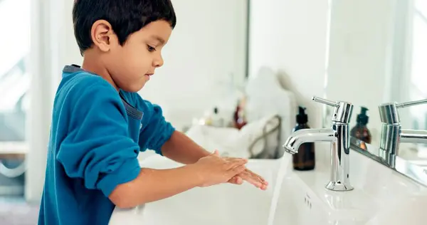 Young boy, washing hands and hygiene for health, sustainability and water at routine at home. Male child, bathroom and clean with soap, foam and sink in healthy with hand washing and disinfection.