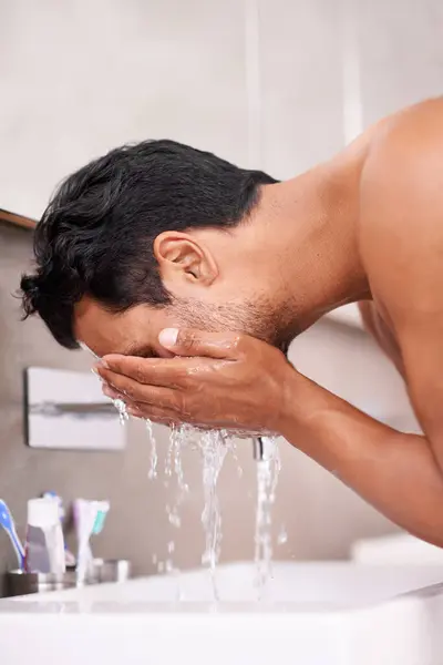 Skincare, splash or man washing face in bathroom for self care, wellness or morning routine. Facial, cleaning or profile of male person at a basin for water, beauty or hydration, cosmetic or results.