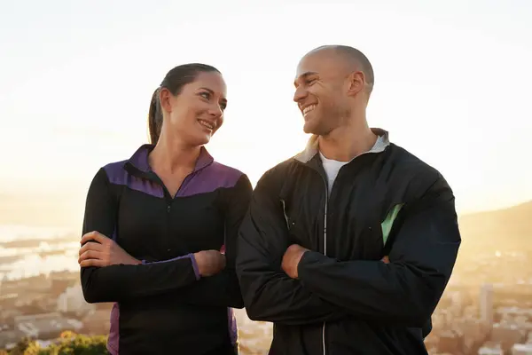 Happy couple, fitness and confidence with sunset on mountain for workout, training or outdoor exercise in nature. Young man and woman with smile and arms crossed for health and wellness together.