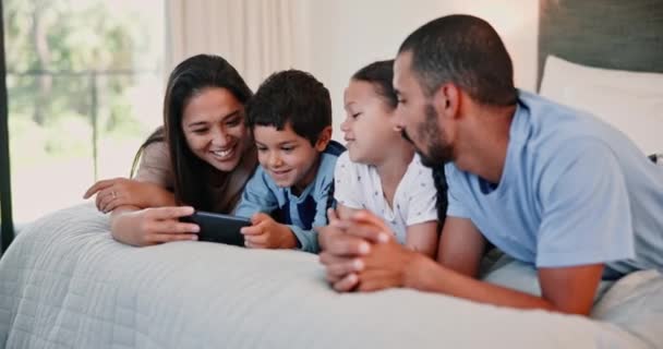 视频和家人在床上与电话观看 直播或一起在酒店度假 通过手机 游戏或社交媒体 流连忘返的父母和孩子们在卧室里放松一下 — 图库视频影像