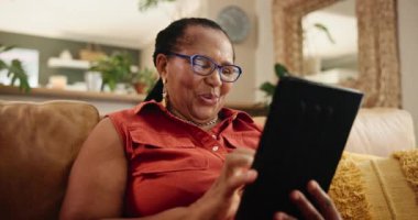 Tablet, arama ve kanepede sosyal medya, mim ya da gif okumak için gözlüklü yaşlı siyahi bir kadın. Dijital, uygulama ve internetteki çizgi romanı, programı veya Netflix 'i olan yaşlı Afrikalı..
