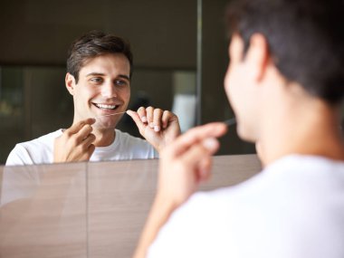 Mutlu adam, diş ve diş bakımı hijyen, tımar ve banyo aynasında tazelik için diş ipi. Ağız, ağız ya da sakız temizliği için düzenli olarak gülümseyen yakışıklı bir erkek yüzü..