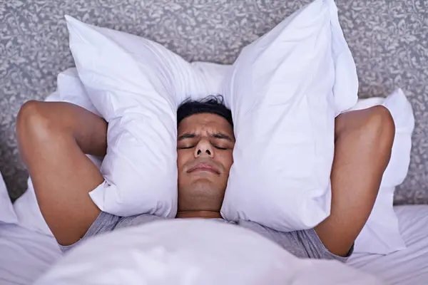 寝室の男 騒音または不眠症は 大きな問題の危機のための枕で休憩したり 疲れたり 耳を覆ったりします サウンドや睡眠の問題 不安や頭痛や家庭でのストレスのために人 イライラし 狂っている — ストック写真